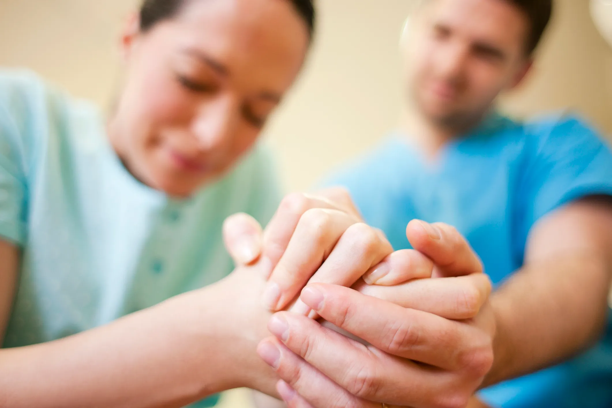 Close-up of a father's hand holding his partner's hand during labor